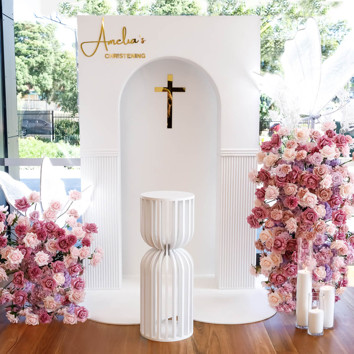 white 3d rectangle arch backdrop with mixed pink and lilac flower arrangements, cake plinth and white sand candles