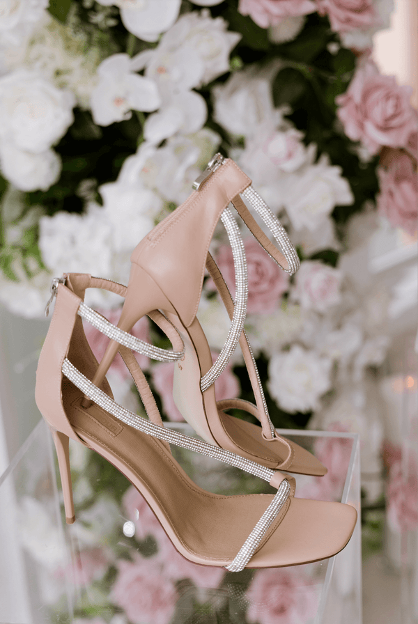 pink heels with diamontes placed on clear plinth with flowers in background