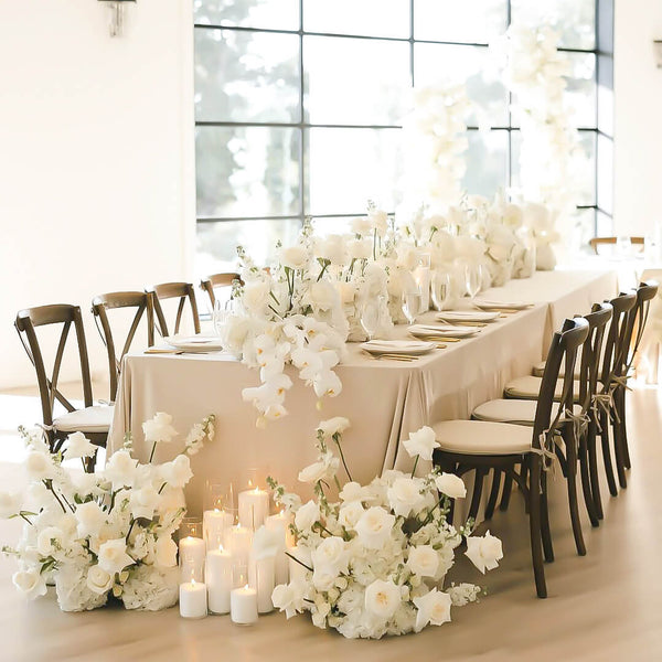 white draping flowers on king table at wedding and sand candles on floor