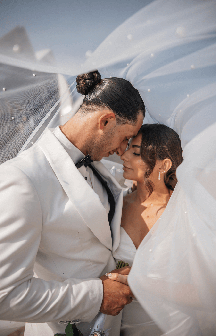 bride and groom touching head to head with brides veil covering both