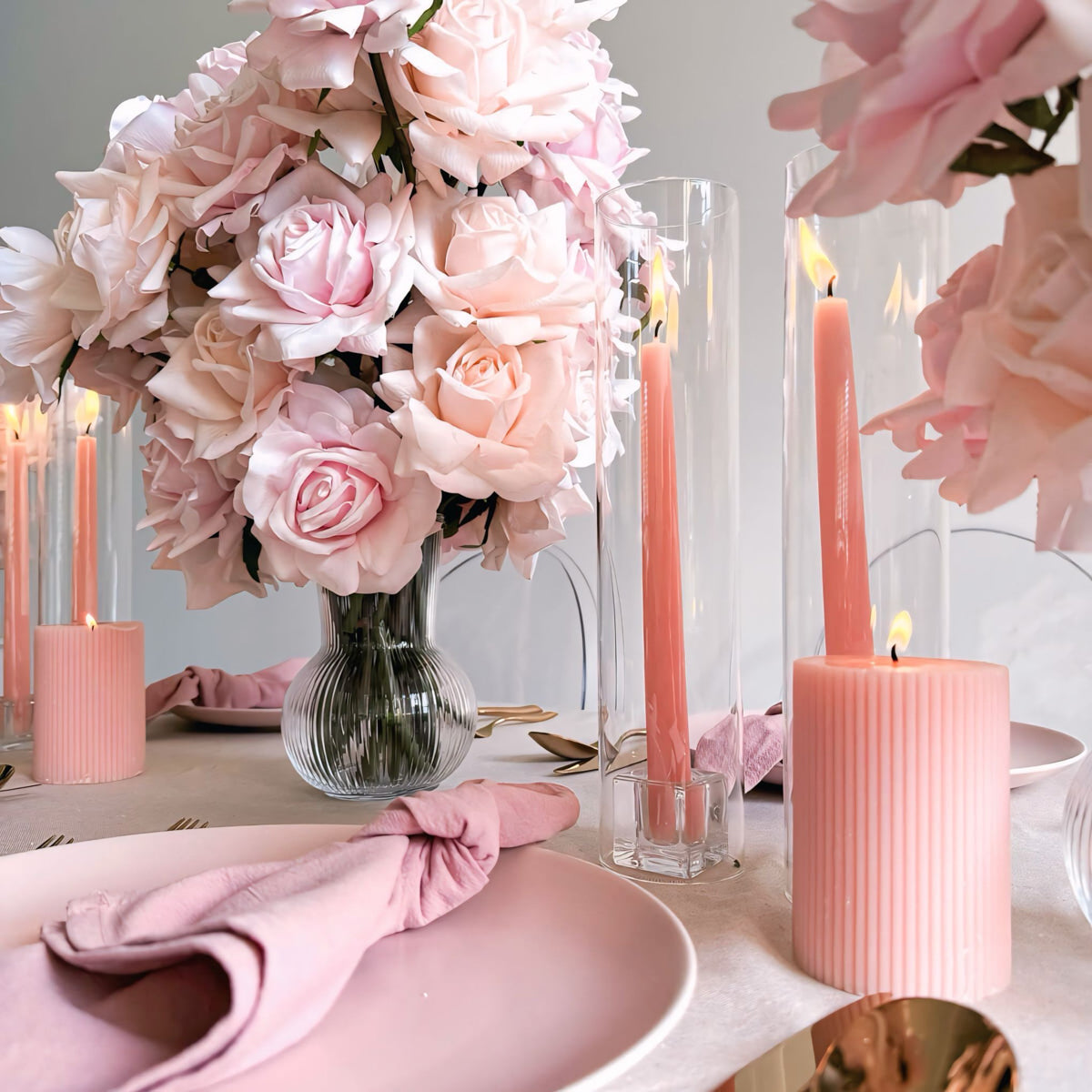 close up image of mixed pink flower arrangement in between pink candles