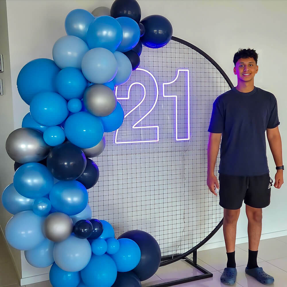 boy standing in front of 21 neon sign on black circle mesh backdrop frame