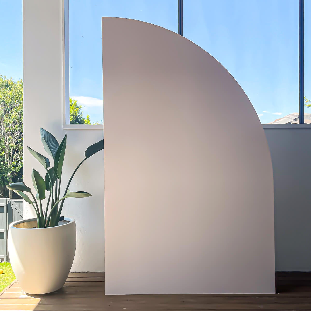 beige sail backdrop standing on timber floor next to pot plant