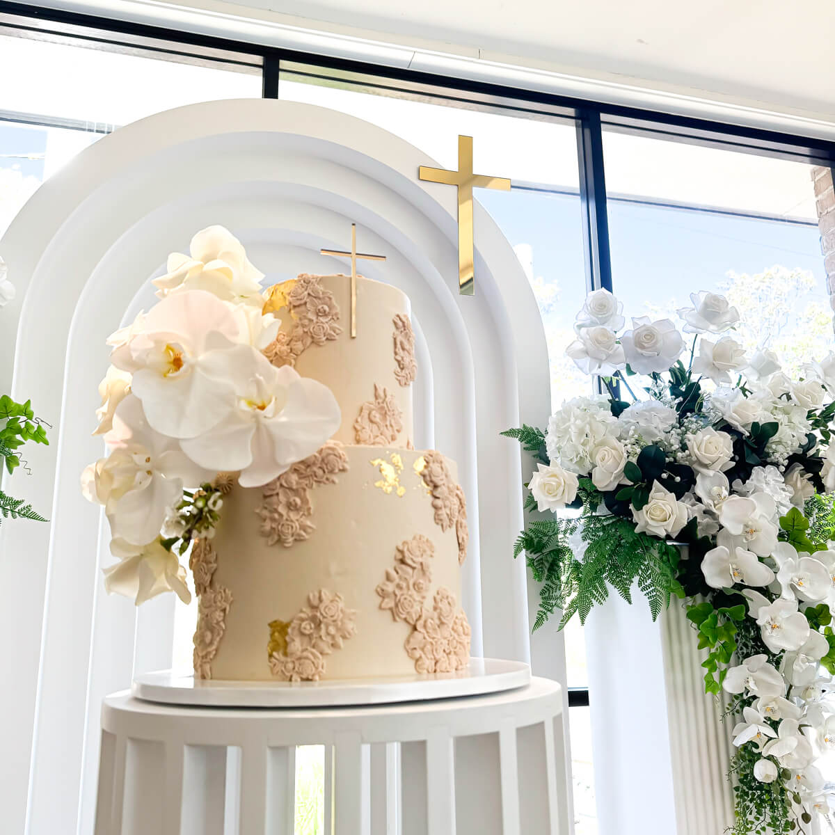 Close up of cake on white ripple plinth with White 3D arch backdrop in backround