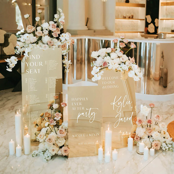three gold mirror welcome signs on floor with flowers and candles