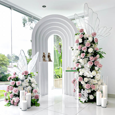 white 3d arch backdrop with pink and white flower arrangements and white led butterflies