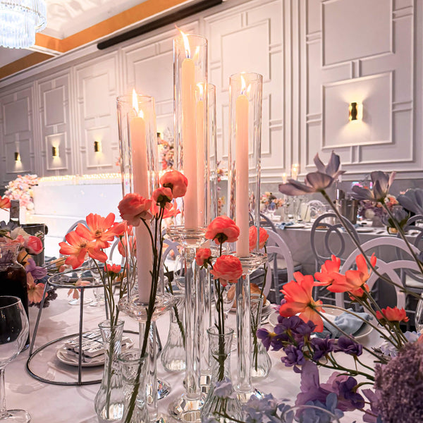 Decorative table setting with crystal taper candle holders and bright flowers in a wedding reception room