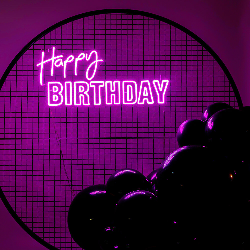 pink happy birthday neon sign on black mesh backdrop frame