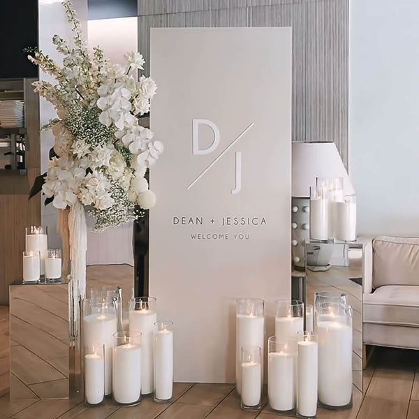 modern rectangle wedding welcome sign in between silver plinths, florals and white sand candles