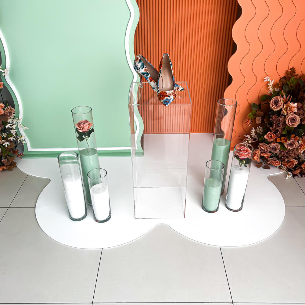 clear plinth, green and white sand candles and coloured backdrops standing on white floor mat